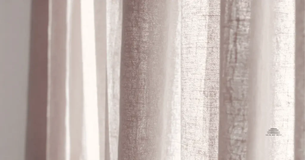 Soft linen curtains illuminated by warm natural light, showing gentle folds and natural fabric texture.