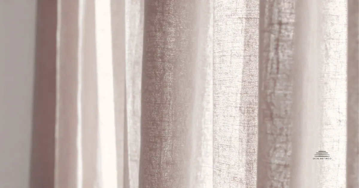 Soft linen curtains illuminated by warm natural light, showing gentle folds and natural fabric texture.
