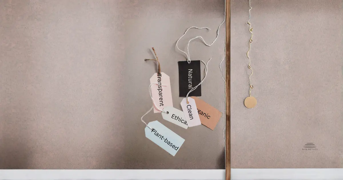 Hanging product-style tags labeled Natural, Clean, Ethical, Transparent, and Plant-based suspended by intertwined strings against a neutral background.