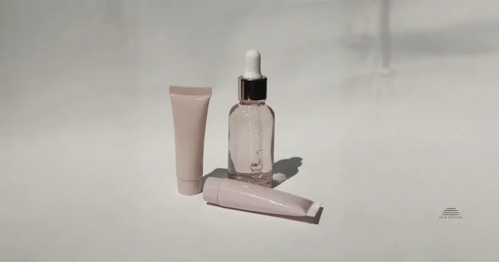 Minimalist arrangement of skincare bottle and tubes against a warm beige background.