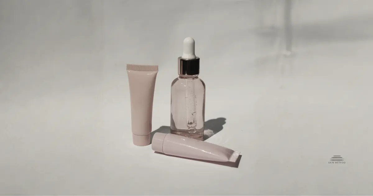 Minimalist arrangement of skincare bottle and tubes against a warm beige background.